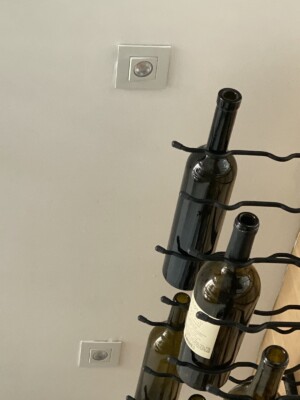 These are the modern recessed lights mounted near and above the wine cellar's metal wine racks.