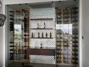 If you look at the cellar closely, there are no standalone embellishments and everything is fixed onto the wall except the bottles. So, what makes this cellar look so modest? It's the careful design and placement of the modern wine racks, the back panel, the glass enclosure, and the floating shelves!
